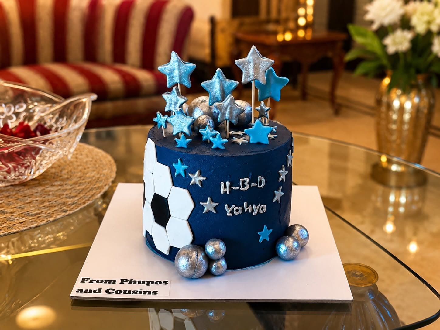 A blue football-themed cake with white ball shapes and blue and silver stars.