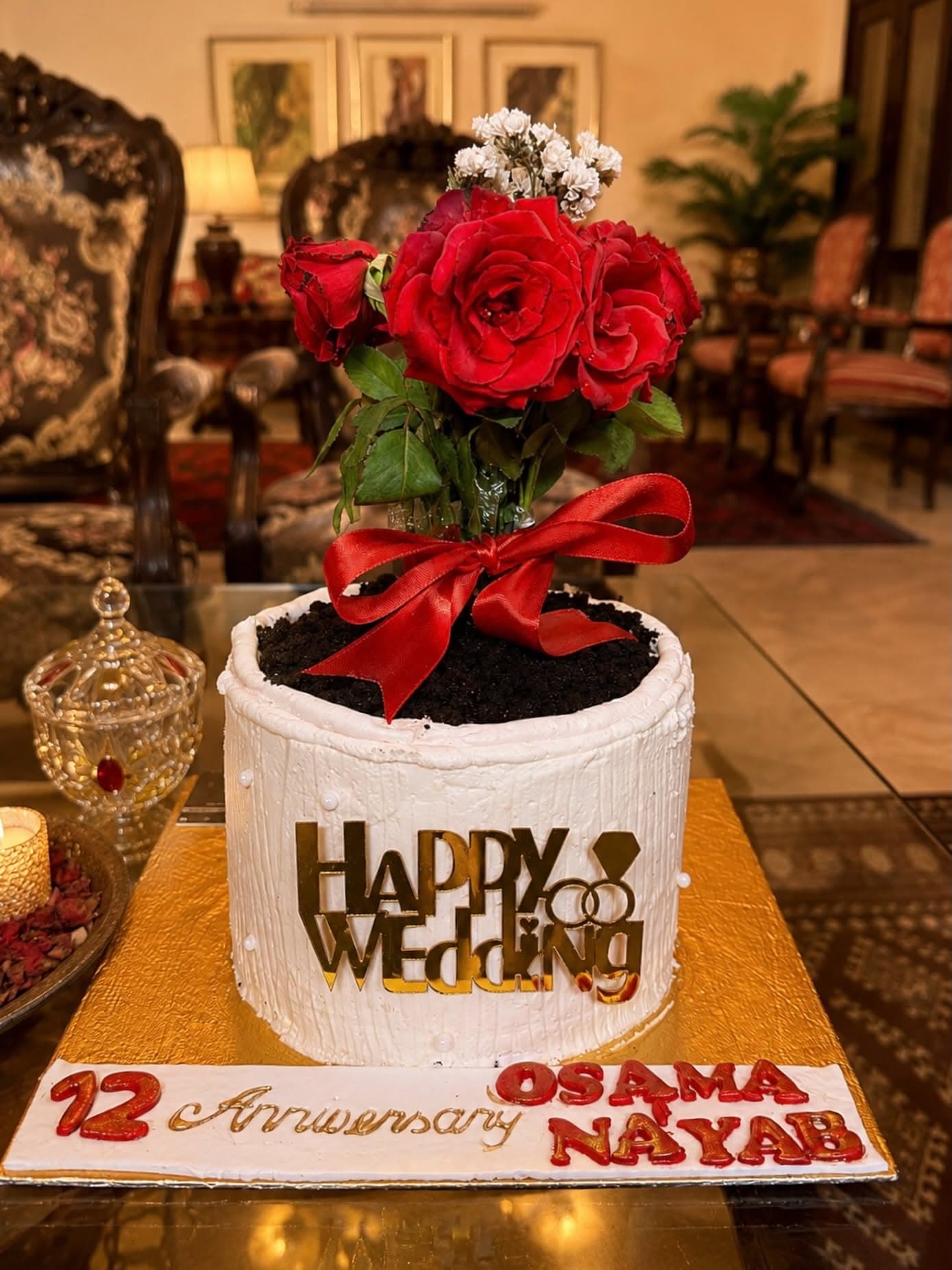 Red roses and ribbon on a white anniversary cake