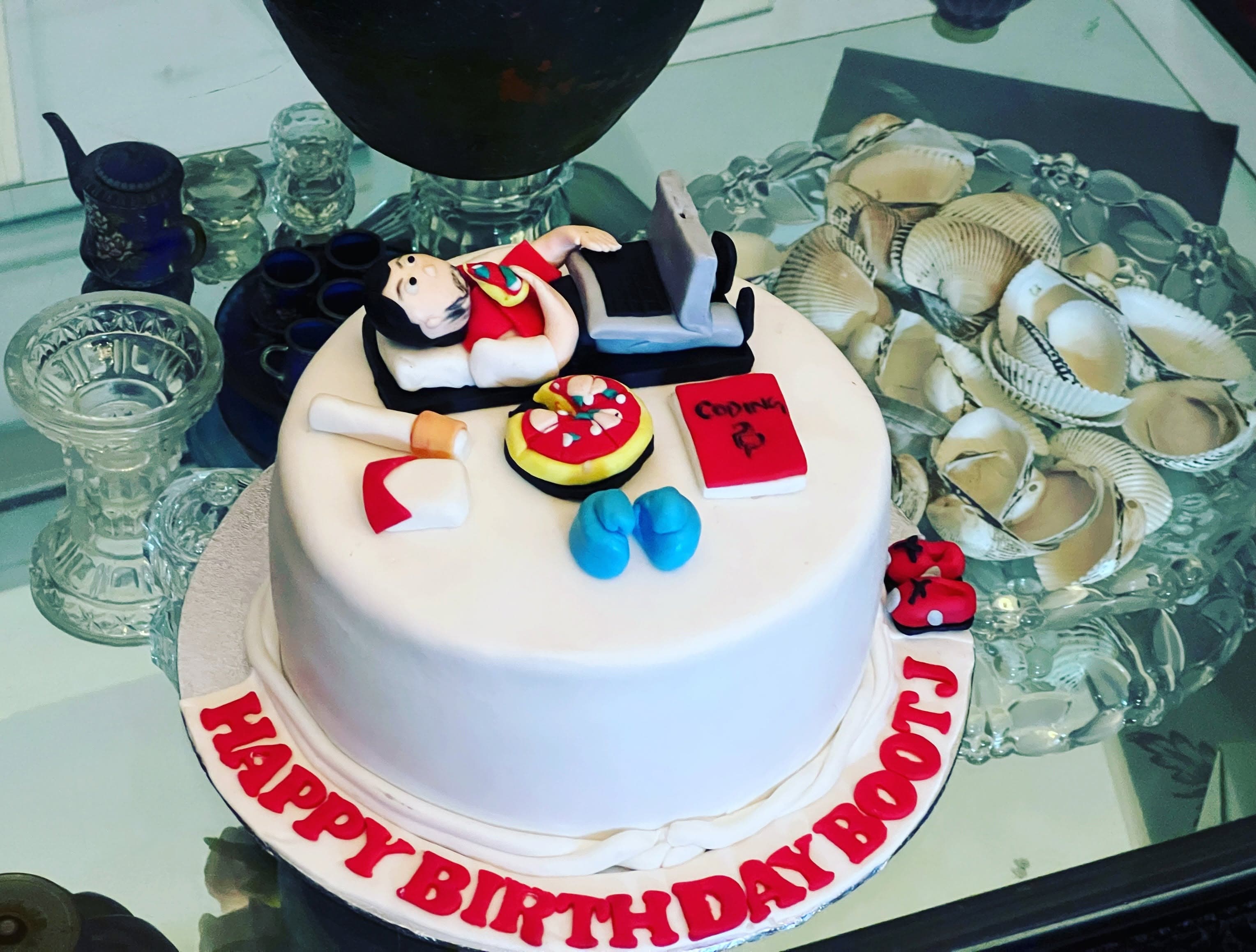 A white round cake topped with miniature food-themed decorations.